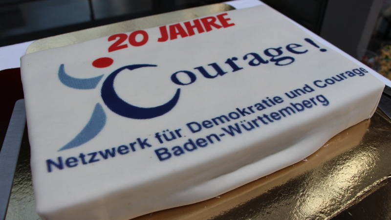 Eine Torte mit dem Aufdruck: 20 Jahre Courage. Netzwerk für Demokratie und Courage Baden-Württemberg.