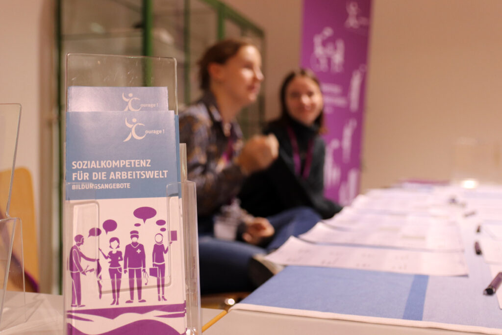 Anmeldestand im Hintergrund, im Vordergrund Flyer des Projekts SKA