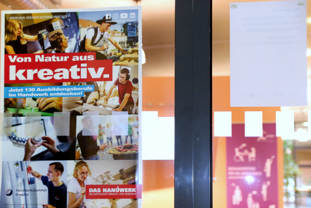 Plakat mit der Aufschrift "Von Natur aus kreativ. - Jetzt 130 Ausbildungsberufe im Handwerk entdecken!" an einer Glastür, im Hintergrund der Eingangsbereich zum 5. SKA-Fachtag