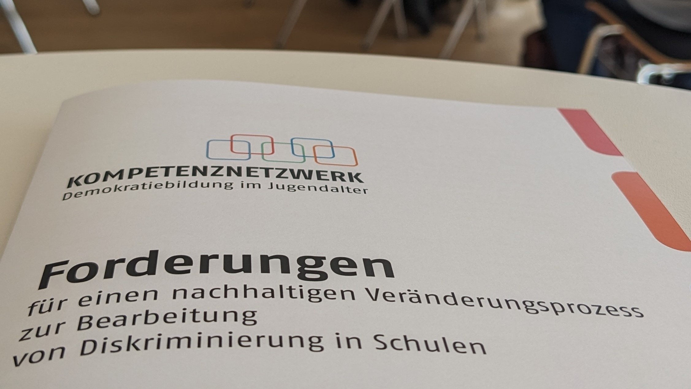 Das Deckblatt der fünf Forderungen für einen nachhaltigen Veränderungsprozess zur Bearbeitung von Diskriminierung in Schulen - auf einem Tisch auf einer Veranstaltung