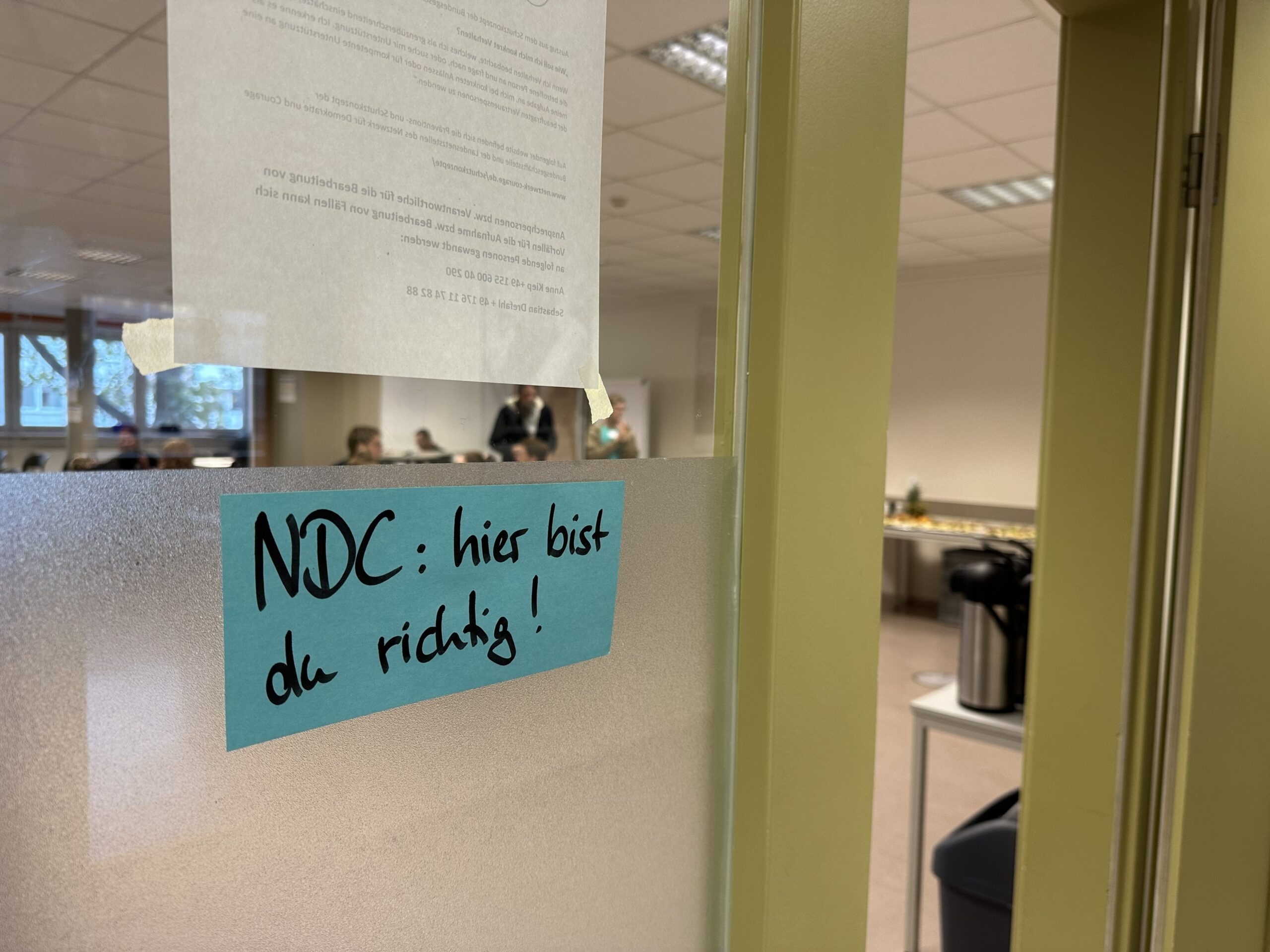 Moderationskarte an einer Scheibe mit der Aufschrift "NDC: hier bist du richtig!"